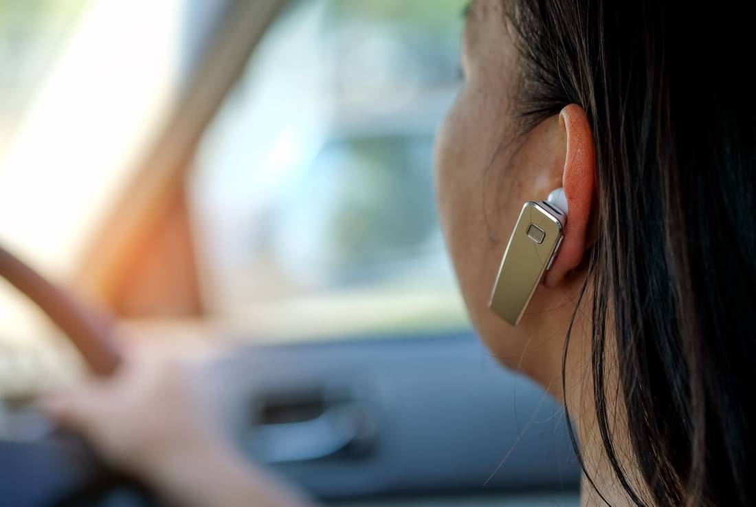 frau im auto mit einem headset für eine freisprechanlage frau im auto mit einem headset für eine freisprechanlage